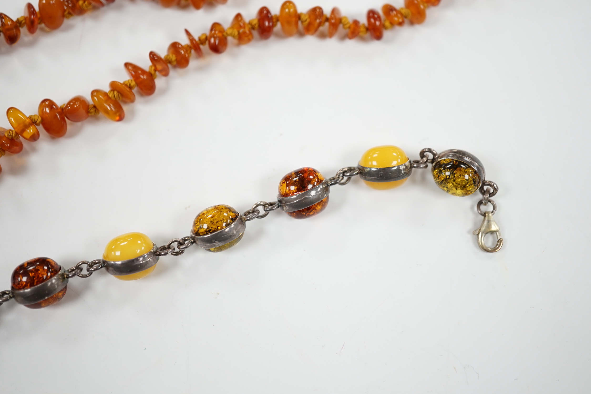 Two white metal and Baltic amber pebble set bracelets, one stamped 925, largest 25cm, a pair of similar drop earrings and an amber necklace.